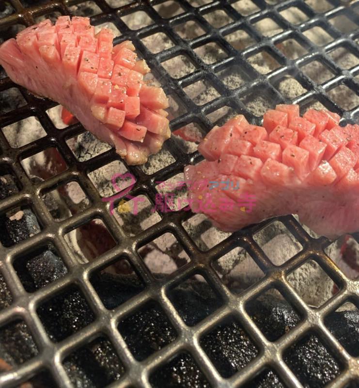 網の上で焼かれている厚切りタンの写真