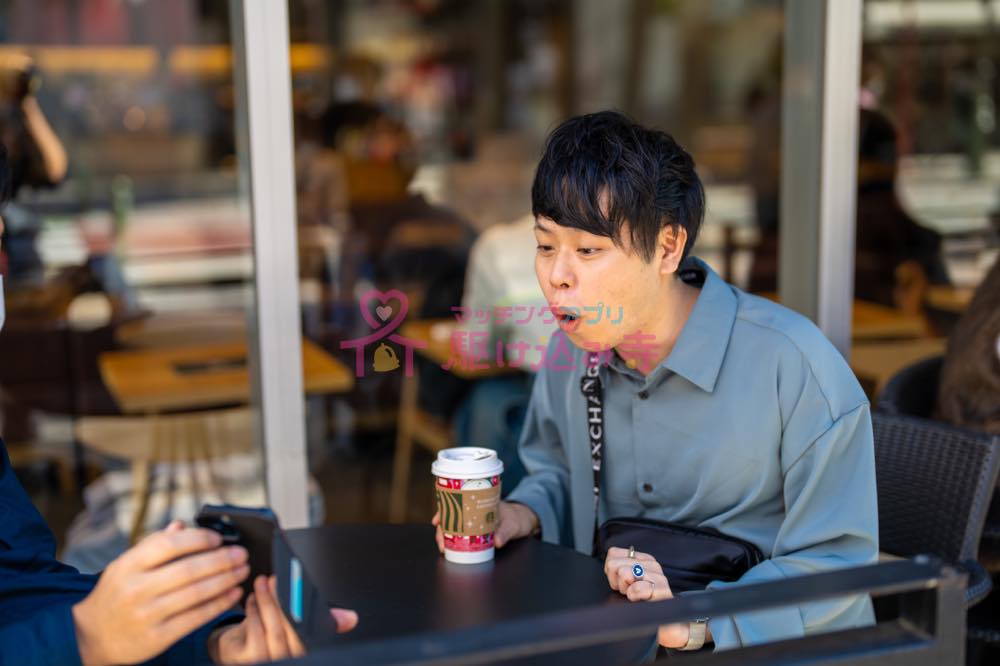 カフェのテラス席で驚く男性