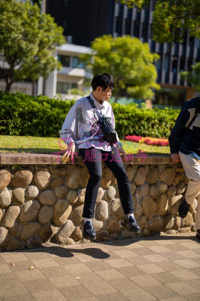 歩道で腰掛ける男性の写真